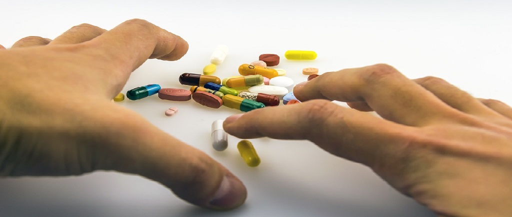 hands grabbing medicine capsules and tablets
